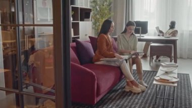 İki beyaz kadın tasarımcının projeleri için tasarım seçerken erkek meslektaşlarının arka planda çalışmalarını yakınlaştır.