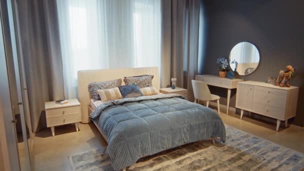 壁に小さな虚栄心と鏡の隣にキングサイズのベッドと青色で作られたモダンな家具付きベッドルームのインテリア — ストック動画