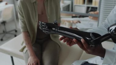 Tanımlanamayan Afrikalı Amerikalı doktor hastasına yeni terzi yapımı yapay kol gösteriyor.