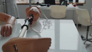 Doktorlar arka planda çalışırken, tıbbi laboratuvarın masasında yatan farklı protezlerin görüntülerini büyüt.