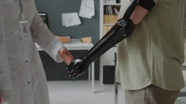 Medikal personel ve uzvu kesilmiş, tanınmayan genç bir kadın arasında orta boy bir el sıkışma.