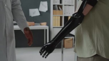 Özel yapım protez kollu tanınmayan bir hastanın yakından görüntüsü. Denetleyici doktorla el sıkışıyor.