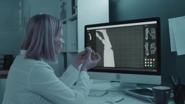小さなプロトタイプを見る3Dモデリングプログラムでコンピュータの後ろに座っている白いコートの女性エンジニア — ストック動画