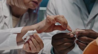 Tanımlanamayan laboratuar çalışanlarının elleri, parmak protezi yaparken birbirleriyle konuşuyorlar.