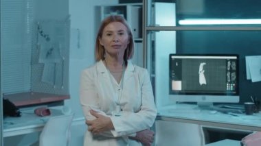 Beyaz önlüklü kadın yüksek teknoloji mühendisinin portresi laboratuarında duruyor ve arkasında 3D model var.