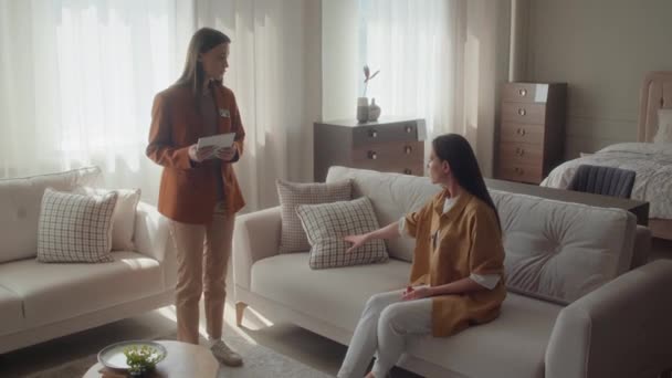 Käuferin Sitzt Auf Weißem Sofa Und Klärt Mit Möbelhausleiterin Über — Stockvideo