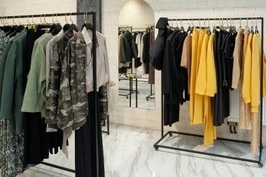 Yeni sezonluk moda koleksiyonu olan iki uzun raf duvarda, aynada ve butikte kameranın önünde duruyor.