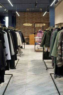 Geniş modern sergi salonunda ya da butikte yeni sezonluk moda koleksiyonunun raflarıyla dolu raflar arasında uzun bir koridor var.