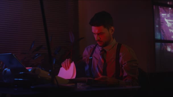 夜のネオンライトルームのテーブルに座っている文書を扱う時代遅れのオフィスワーカーの中側ショット — ストック動画