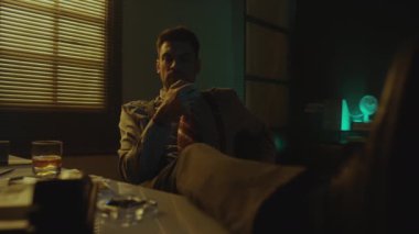 Orta boy beyaz sakallı bekar akşamı tek başına içki içerek ve geceleri ayakları masada pipo içerek geçiriyor.