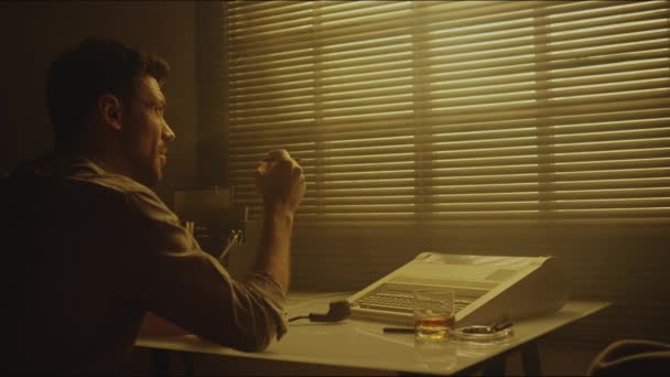 塞皮亚回头看了看身穿衬衫的白人 一边抽烟一边望着别处 然后在昏暗明亮的房间里 坐在桌子旁 用打字机看书 — 图库视频影像