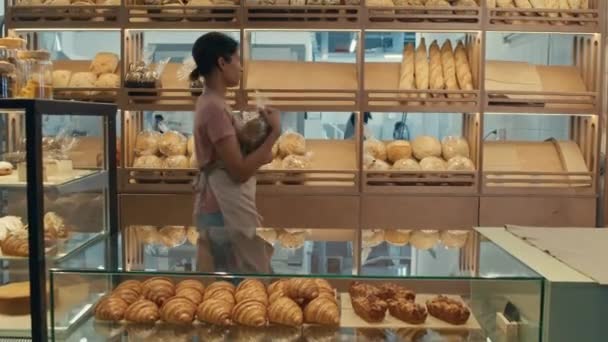 Zoom Ditembak Pekerja Perempuan Muda Celemek Menempatkan Roti Segar Rak — Stok Video