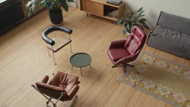小さなコーヒーテーブルの周りに木製の床とアームチェアを備えたモダンな快適なオフィスのハイアングルビュー そこに人がいない — ストック動画