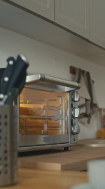 Tanımlanamayan ellerin dikey olarak fırını kapatması ve ev mutfağında sıcak yemek yemesi.