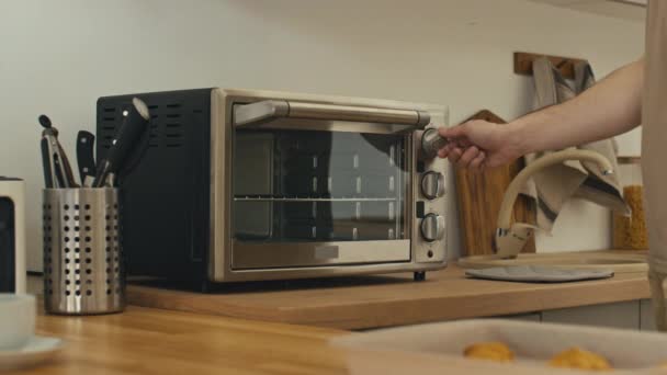 一个无法辨认的男人打开烤箱 在烤盘上放上饼干 然后离开了 中间部分被刺伤的镜头 — 图库视频影像