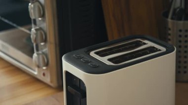 Modern mutfakta kahvaltı hazırlarken, iki dilim beyaz ekmeği tost makinesine dolduran erkek elleri yüksek açılı bıçak açısı.