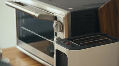 Tanınmayan bir adamın, tost makinesinden taze kızarmış ekmek alıp tabağa koyduğu ve sonra da modern mutfağa giden fotoğrafının yan görüntüsü.