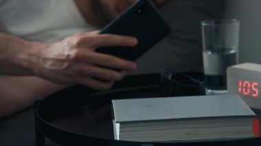 Geceleri evde uyumadan önce akıllı telefonu şarja takan tanınmamış bir adamın yan bıçak görüntüleri.