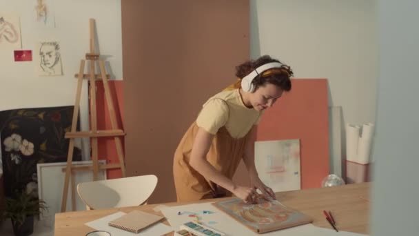 Kulaklıklı Mutlu Beyaz Kadın Ressamın Stüdyoda Boya Kalemleriyle Resim Çizerken — Stok video