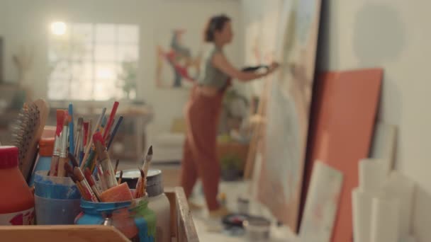 アーティストツール ブラシ スタジオのペンキ ジャンプスーツで認識できない女性デコレータのクローズアップセレクティブフォーカスショット — ストック動画