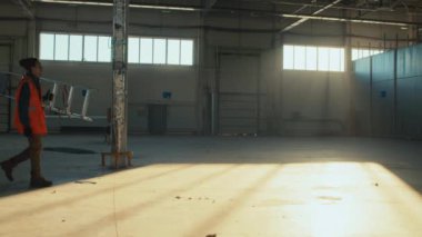 Tanımlanamayan inşaat işçisinin merdiven ve elle boş bir odayı geçerken tam boy yan görüntüsü.