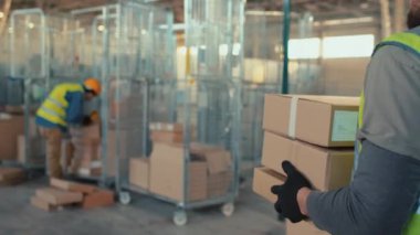 Tanımlanamayan bir depo çalışanının, iş günü karton kutularda eşya taşırken çekilmiş görüntüleri.