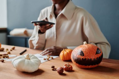 Korkunç suratlı ve masada uzanmış çizim yapan genç bir kadının resmini çeken ürkütücü Cadılar Bayramı balkabağı.