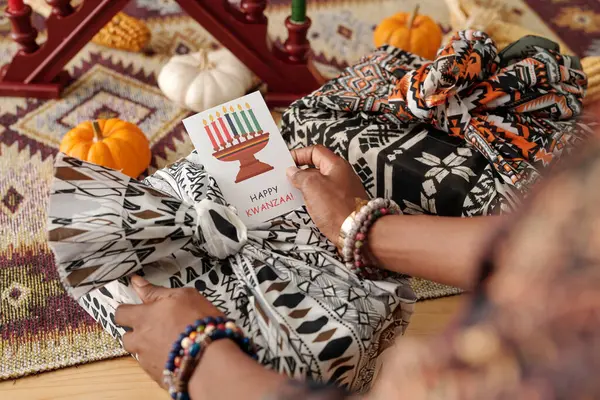 Dłoń Młodej Afroamerykanki Trzymającej Kreatywną Pocztówkę Kwanzaa Świecznikiem Nad Zapakowanym — Zdjęcie stockowe