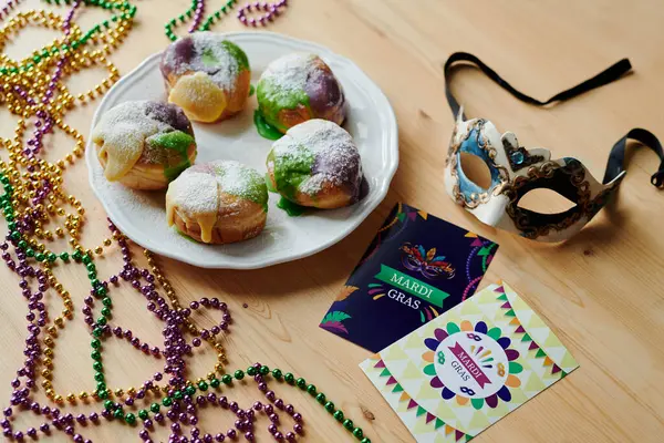 Venetian mask, greeting postcards, appetizing donuts and beads of yellow, purple and green color prepared for celebration of Shrove Tuesday