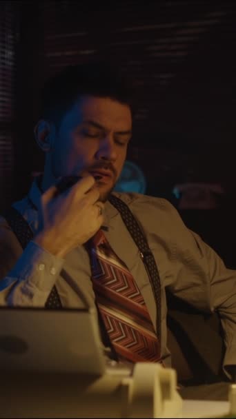 复古风格的困惑的白种人留胡子男子的竖直手持照片 晚上坐在桌旁 手里拿着烟斗在黑暗的房间里 — 图库视频影像