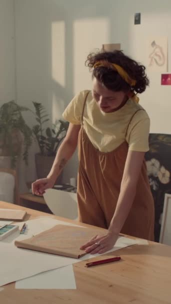 身着连衣裙的中年白人女艺术家站在车间桌子旁 用彩绘素描 然后退后一步 看看结果 转过来的照片 — 图库视频影像