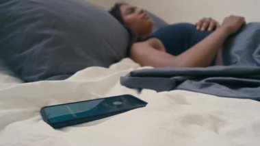 Genç Afrikalı Amerikalı bir bayanın telefon alarmına uyanıp üzerinde 