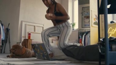 Siyah kızın pijamalarıyla yatakta oturup yemek yerken Wabi Sabi 'nin dairesindeki evcil hayvanın yanında bilgisayar başında film veya video izlediği bir sahne.