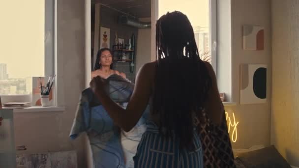 ミラーの前に立っている若いアフリカ系アメリカ人女性のバックメディアビューグラウンジロフトアパートで準備しながら着るシャツを選択 — ストック動画