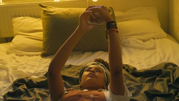Средний Снимок Афроамериканской Женщины Лежащей Удобной Кровати Смотрящей Отражение Экрана — стоковое видео