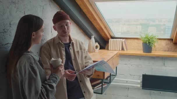 中等比例的白人青年男女站在屋顶窗户旁边的阁楼上 讨论业务介绍 聊天和大笑 — 图库视频影像