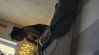 Genç siyahi bir bayanın neon yazıyla yatakta oturduğu görüntüler. Sadece duvarda 