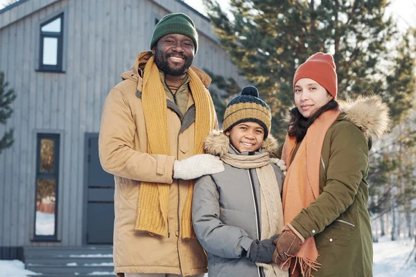 冬休みを楽しんでいる彼らの幸せなかわいい息子を取り囲む暖かい冬のウェアで陽気な若い異文化の母親と父親 — ストック写真