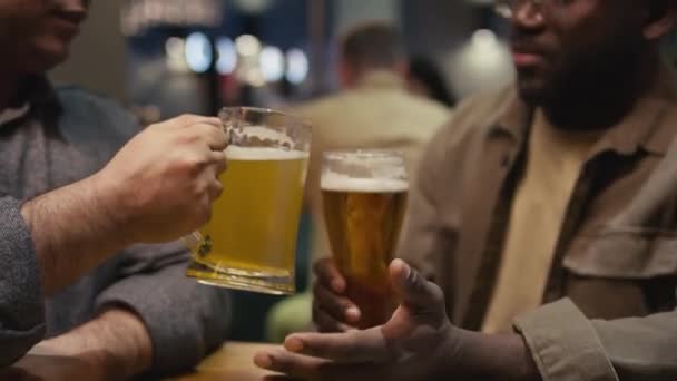パブに座っている黒人と白人同僚のキルトクローズアップは 仕事の後の夕方にビールでメガネを飲みながら話す — ストック動画