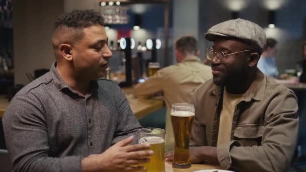 バーでビールを飲みながら親密な話をするBiracialとアフリカ系アメリカ人の親友のミディアムショット — ストック動画