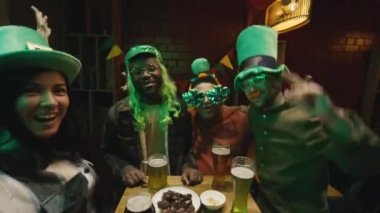 UGC POV, yeşil peruk ve komik gözlükler takan ve masada yeşil bira bardaklarıyla dans ederken Aziz Patrick Günü 'nü kutlayan bir grup çok ırklı arkadaşın el kamerasıyla çekilmiş görüntüleri.