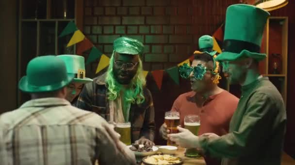 バーでグリーンビールを飲む多様な友人と国民的なアイルランドの聖パトリックの日を祝う女性にスタウトアレを提供する男性バーテンダーのメディア映像 — ストック動画
