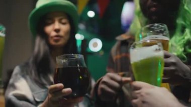 Kapalı alanda Aziz Patrick Günü kutlamalarında yeşil bardakları tıkırdatan ve bira içen kimliği belirsiz arkadaşlarımızın yavaşlaması.