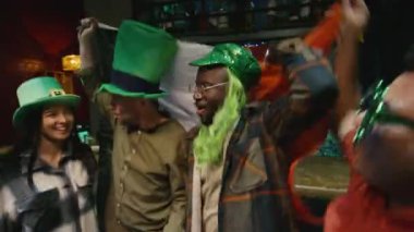 Yeşil şapkalı çeşitli arkadaş grupları İrlanda bayrağıyla birlikte barda Aziz Patrick Günü 'nü kutluyor.