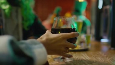 Kadın elinin bir bardak şarap, bira ya da siyah bira alıp St. Patrick 'in bardaki partisinde barın arkasına koyduğu yakın plan.