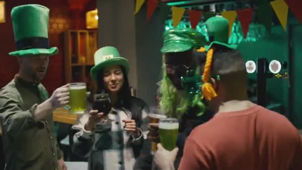 不同成人朋友戴着绿帽跳舞和碰杯啤酒的中等镜头 — 图库视频影像