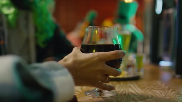 女性の手のサイドクローズアップワイン スタウトエールまたはブラックビールのグラスをとり パブでセントパトリックデイパーティー中にバーカウンターに戻します — ストック動画