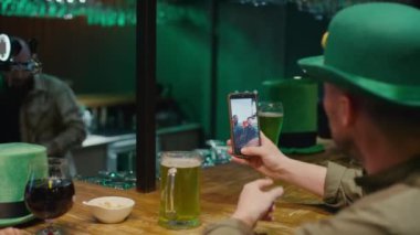 Kimliği belirlenemeyen yeşil şapkalı bir adam ve kadının, İrlandalı dostlarını arayıp barda yeşil birayla kutlama yaparken video aracılığıyla Aziz Patrick Günü 'nü kutlarken görüntülerinden.