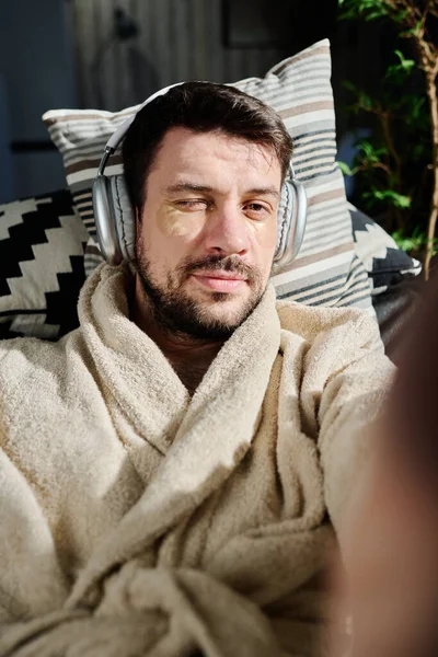 Relaxed Guy Headphones Bathrobe Lying Couch Front Camera Communicating Video — Stock Photo, Image