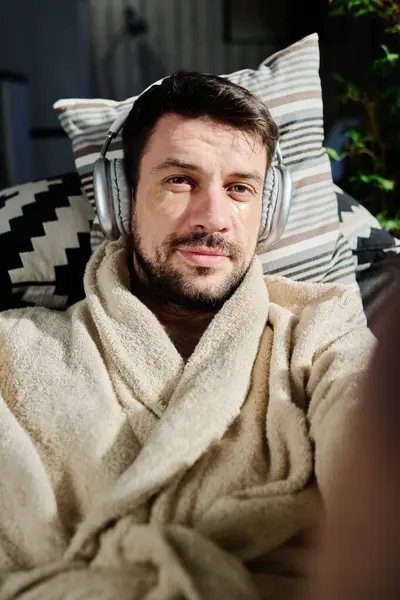 Relaxed Young Man Headphones Bathrobe Lying Couch Looking Camera Skincare — Stock Photo, Image